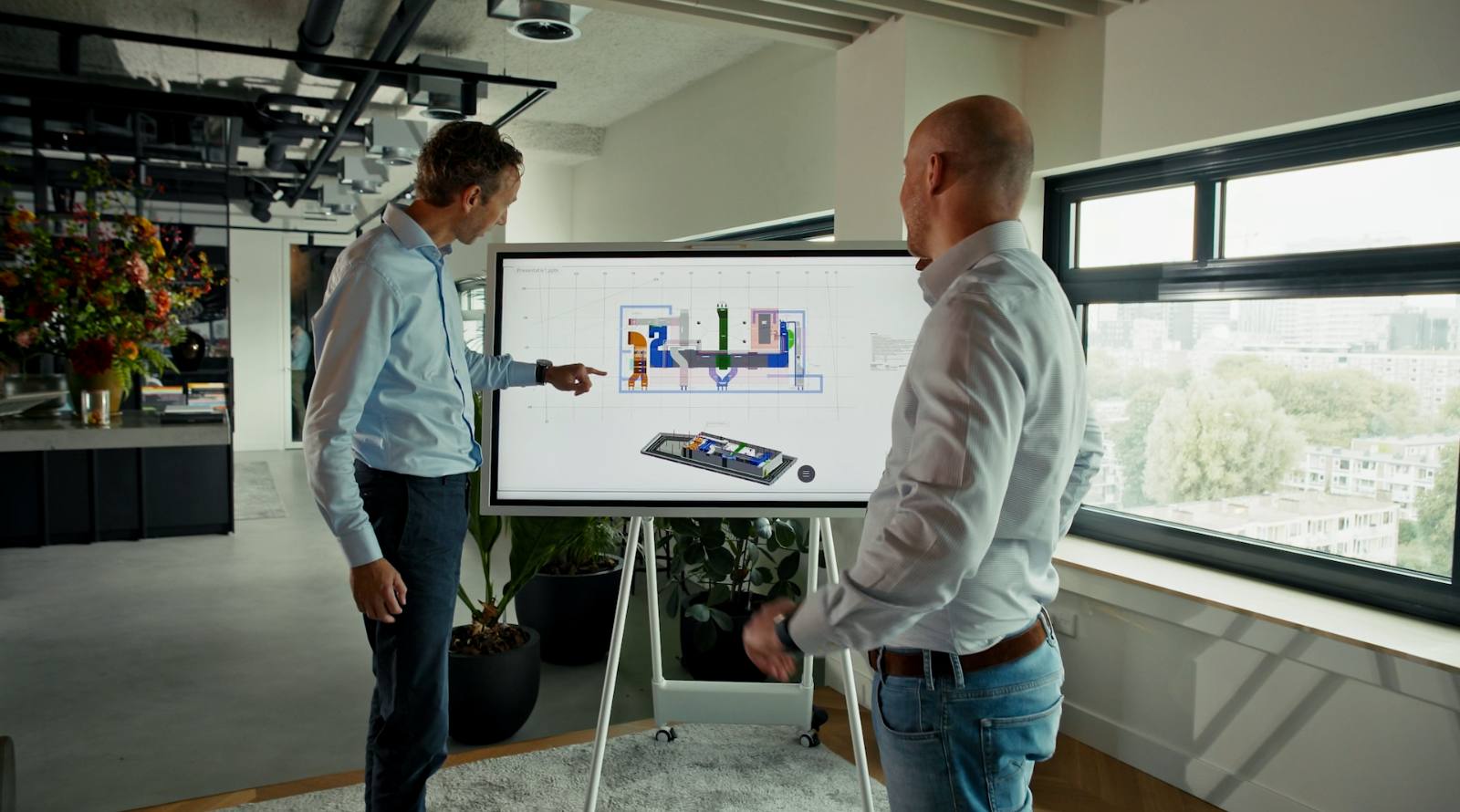 Twee NEOO-collega's bespreken een BIM-model op een digitaal scherm