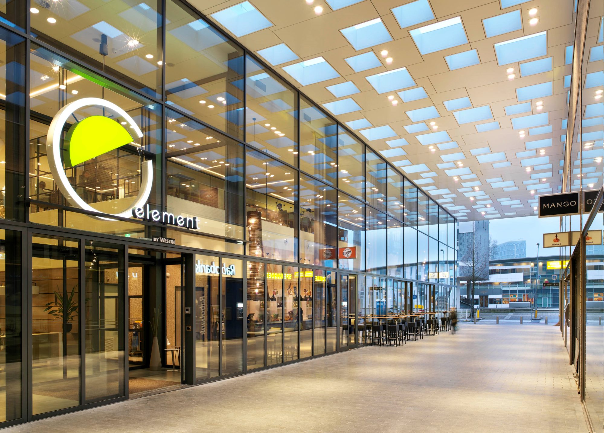 De entree van Element Hotel onder de verlichte luifel van het winkelcentrum