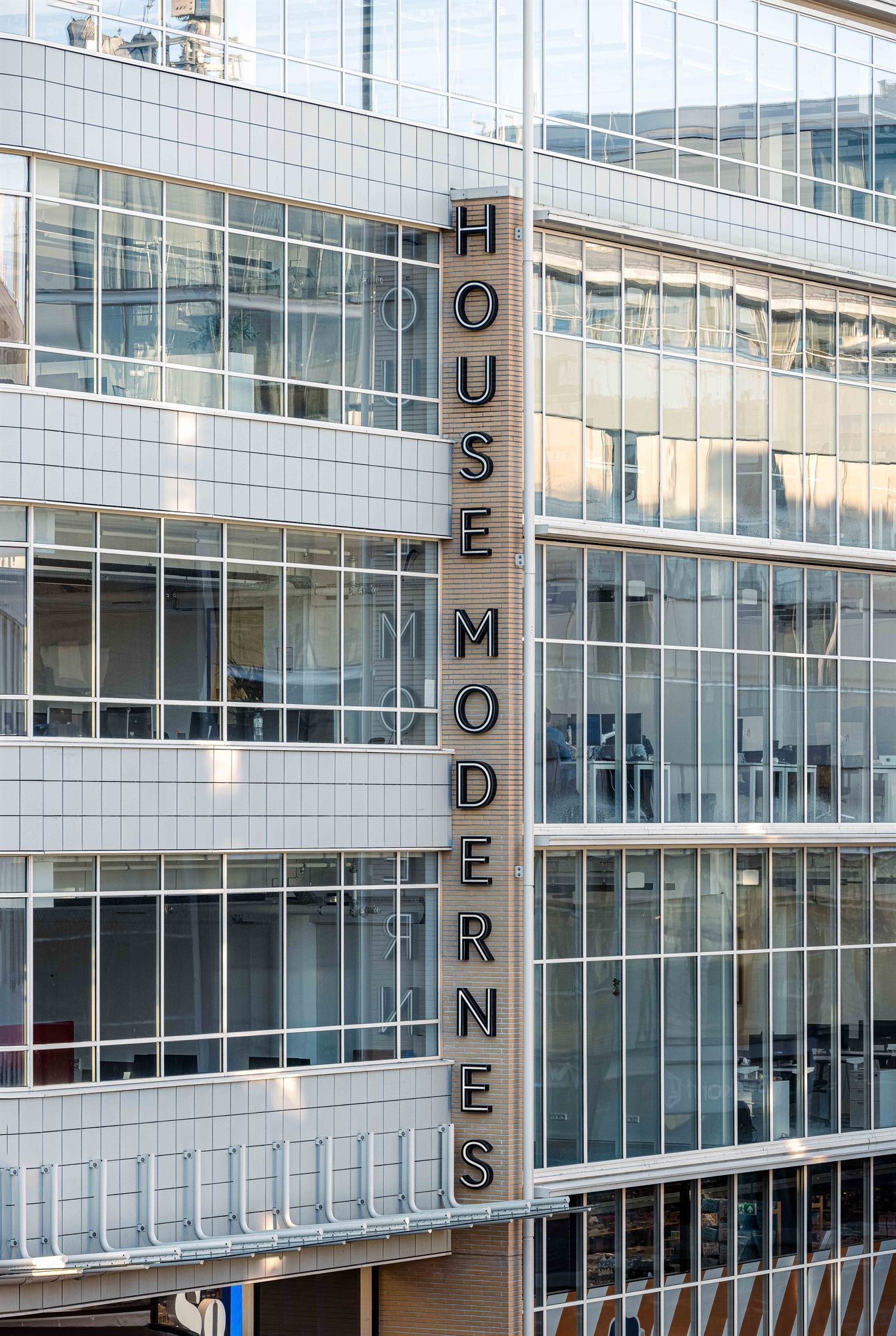 De verticale gevelletters HOUSE MODERNES op de glazen gevel